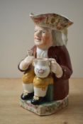 A 19th century Toby Jug, depicting a man seated in 18th-century attire holding a white frothing jug,