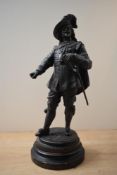 A large patinated metal study of a cavalier or musketeer, raised on circular wooden base, measures
