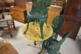 A traditional cast aluminium garden table of circular form , coated in yellow and a set of four
