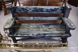 A traditional garden bench having promenade style metal frame and wooden slatted seat , arms and