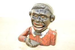 A late 19th-century cast iron 'Little Joe Bank', featuring a mechanical lever that lifts the hand to