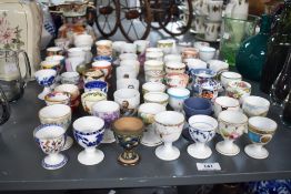 A large selection of 19th and 20th-century ceramic egg cups, some transferware and some hand-