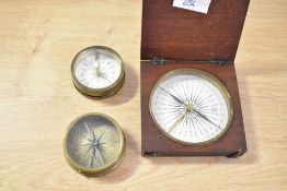 Three 19th-century brass pocket travel compasses, to include a mahogany, hinged lid case example,