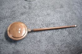 An early 20th-century turned wood and copper bed warming pan, 121cm, condition is consistent with