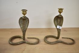 Two 20th-century Indian brass cobra snake candlesticks, each of coiled textured form with coloured