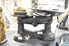 An Edwardian cast iron balance scales, featuring a copper bowl and five brass graduating weights,