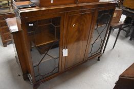 An early 20th century mahogany side-by-side bookcase, the two astragal glazed end sections enclosing