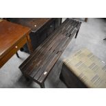 An oblong teak bench, by A Lister & Co, having slatted top and simple tapering square section