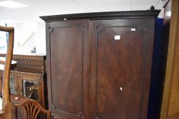 A George III mahogany press cupboard, having a dentil moulded frieze over two re-entrant panelled