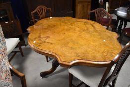 A Victorian figured walnut loo table, of oval serpentine outline with hinged action over the