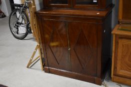 A late 19th/early 20th century glazed mahogany bookcase over cupboard, having a scroll and tablet