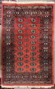 A vintage hand knotted Bokhara rug in red, black, blue and cream wool, having a central Gul repeat