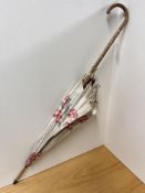 Antique parasol in cream with pink florals, worked wooden handle, has significant tearing to the