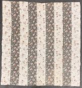 An antique Durham quilt in striped patchwork of unusual textured floral fabrics, a green gounded