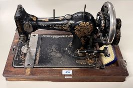 A vintage Jones Family hand-crank sewing machine with spare spools and attachments, in mahogany