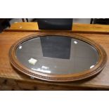 Local interest* Ernest John Oldcorn, an Arts & Crafts oak framed and bevelled mirror, of oval form