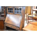 An early 20th Century oak bureau having display upper section with leaded glass doors over drop flap