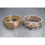 Two silver hinged bangles, one of broad form with engraved floral decoration, the other having an