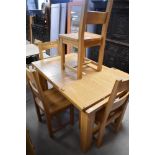 A modern golden oak extending dining table and four similar solid seat rail back dining chairs,