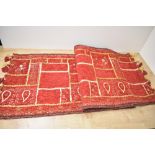 A small vintage Turkish-style runner rug, featuring red and gilt stitching of traditional motifs,