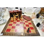A 20th-century Staunton-style hand carved wooden chess set, featuring a red and gilt board with