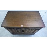 A modern Old English style oak cabinet with a hinged lid, over a pair of cupboard doors, raised on