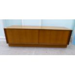 A G-Plan teak cabinet with a pair of sliding doors, on a plinth  18"h  60"w