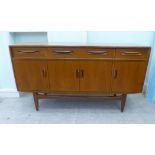 A G-Plan teak sideboard with three frieze drawers, over four cupboard doors, raised on tapered legs