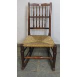 A 19th Century elm country spindle back rocking chair with rush seat. H96cm x W49cm x D63cm