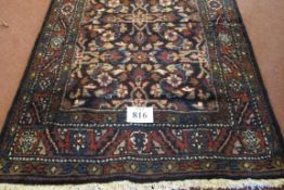 A Persian wool rug/runner with a central floral field and wide borders. 338cm x 109cm approx.