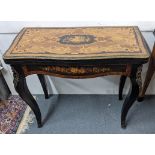 A 20th century French ebonized and marquetry inlaid fold over card table having a mixed veneer