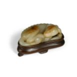 A Chinese pale green and russet jade figure of a recumbent dog, probably Ming Dynasty,