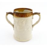 A 19thC two tone stoneware loving cup tankard, the body moulded in relief with tavern scenes with