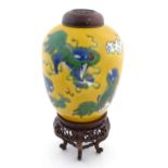 A Chinese yellow glazed vase decorated with foo dogs / guardian lions, with a carved hardwood lid