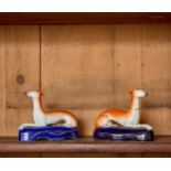 A PAIR OF STAFFORDSHIRE RECLINING GREYHOUND SPILL VASES OR PEN HOLDERS