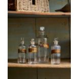 A SELECTION OF FOUR GLASS APOTHECARY BOTTLES WITH RECTANGULAR STOPPERS
