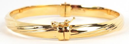 An as new 9ct gold hinged bangle retailed by Goldsmiths, with box, 6cm wide, 6.0g.