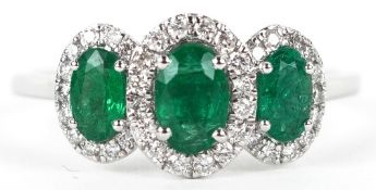 A platinum emerald and diamond trilogy ring, total diamond weight 0.22 carat, total emerald weight