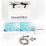 A Pandora silver charm bracelet with a large selection of charms including teddy bear, watering can,