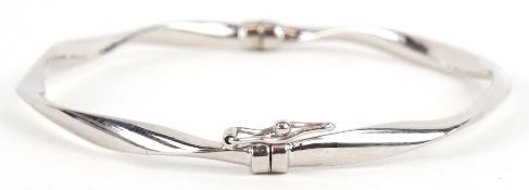 An as new 9ct white gold hinged bangle retailed by Goldsmiths, with box, 6.5cm wide, 3.2g.
