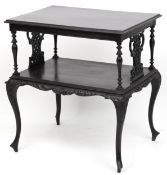An early 20th century ebonised two tier side table with carved decoration, raised on cabriole