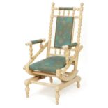 An early 20th century American cream painted rocking chair with upholstered seat and back, 112cm