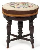 A late Victorian mahogany revolving piano stool with tapestry seat, raised on reeded legs, 44cm high