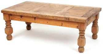 A 20th century rectangular pine coffee table raised on turned block legs, 40cm H x 110cm W x 61cm