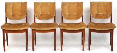 A set of four mid 20th century teak dining chairs with overstuffed seats, raised on tapering legs,