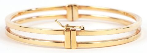 An as new 9ct gold openwork hinged bangle retailed by Goldsmiths, with box, 6cm wide, 4.8g.