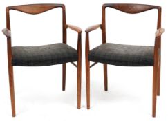 A pair of mid 20th century Danish rosewood elbow chairs, each with overstuffed seats, raised on