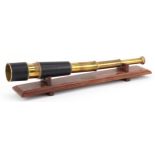Naval interest leather bound brass three draw telescope on display stand, 48cm in length extended.