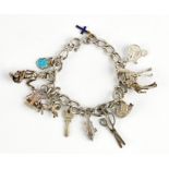 A silver charm bracelet with eleven charms, including a pair of scissors, a swan, a fish, a key,