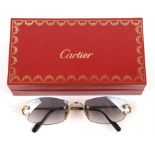 A pair of Cartier sunglasses, rimless frames with irregular shaped tinted lenses,